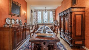 A dining room with a long wooden table set for six, flanked by wooden cabinets and a patterned rug. - Maison Koch · Maison bourgeoise - 240 m2 (Strasbourg)