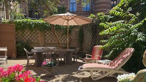 An outdoor patio with a table and chairs, a lounge chair, and a decorative statue. - Maison Koch · Maison bourgeoise - 240 m2 (Strasbourg)