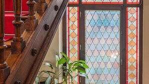 A wooden staircase with a red carpet, a stained glass window, and a potted plant. - Maison Koch · Maison bourgeoise - 240 m2 (Strasbourg)