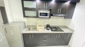 Uma cozinha compacta equipada com geladeira, pia, micro-ondas e fogão a gás.