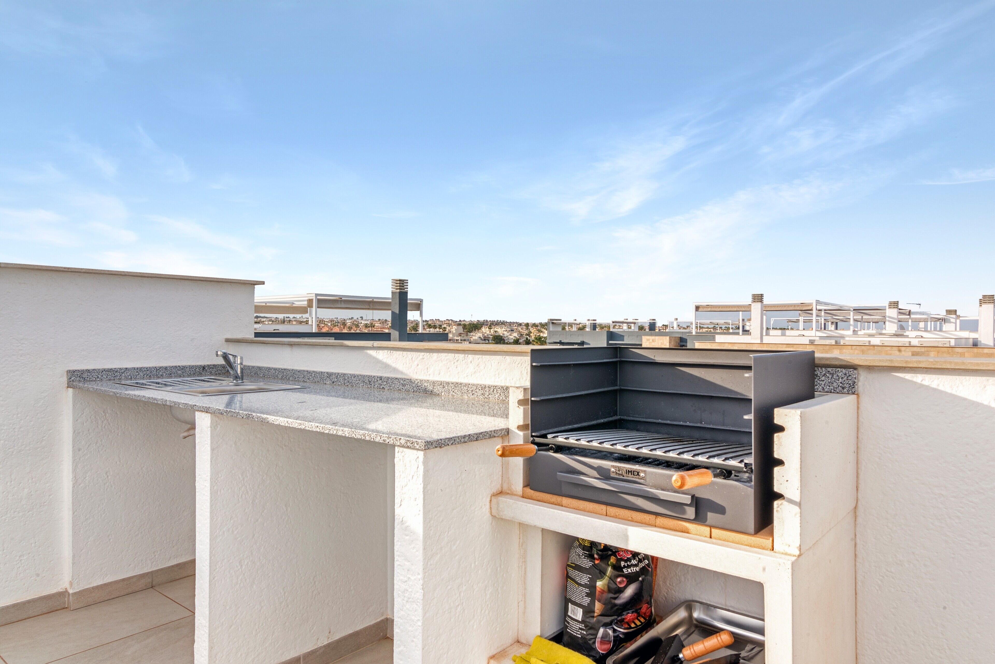 Una terraza con una parrilla incorporada, un lavabo y vistas a la ciudad.