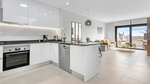 Een moderne keuken met inbouwapparatuur, een eethoek met een bank, en een groot raam met uitzicht over de stad.