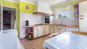 A compact kitchen with white cabinets, a built-in oven, and a window overlooking a green landscape.