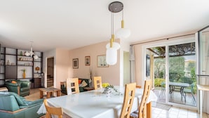 A dining area with a table, chairs, and a hanging light fixture.