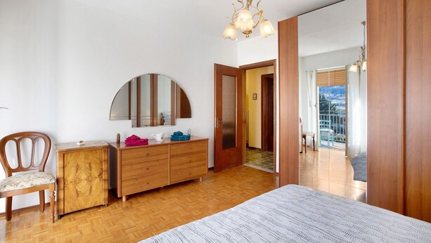 A bedroom with a wooden dresser, a chair, a bed, a mirror, and a chandelier. - Apartment 'Maison Blanchet' with Mountain View and Balcony (Sarre)