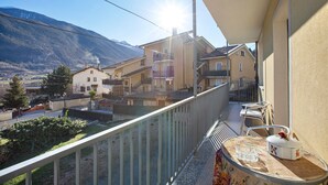 A balcony with a view of a mountain, a table with a flower vase, and a chair. - Apartment 'Maison Blanchet' with Mountain View and Balcony (Sarre)