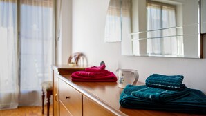 A wooden dresser with folded towels, a white mug, and a mirror reflecting a window with curtains. - Apartment 'Maison Blanchet' with Mountain View and Balcony (Sarre)
