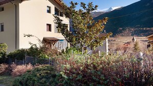A multi-story building with balconies, surrounded by dense shrubbery and a mountain backdrop. - Apartment 'Maison Blanchet' with Mountain View and Balcony (Sarre)