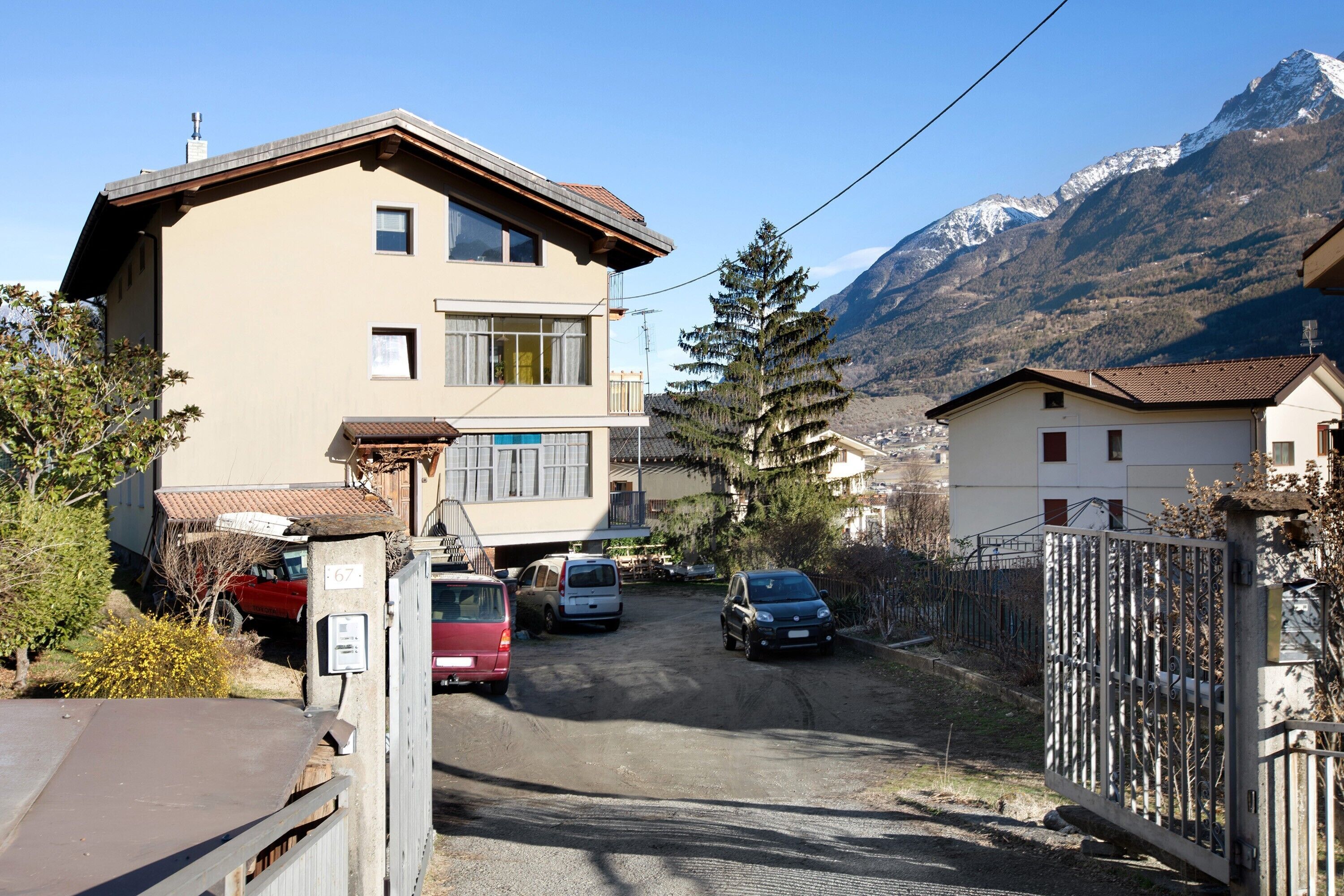 A two-story building with a sloped roof, a garage, and a fenced driveway.