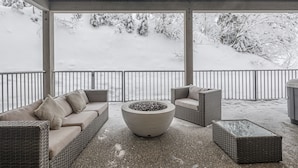 A covered outdoor seating area with wicker furniture and a central fire pit. - Modern Duplex w/ private hot tub, EV charger & media room - pet friendly too! (Silver Star Mountain)