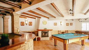 Un tavolo da biliardo in una stanza con camino, travi in legno e parete in mattoni.