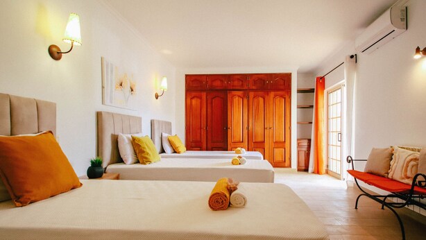 Una camera d'albergo con due letti, una panca e un armadio.