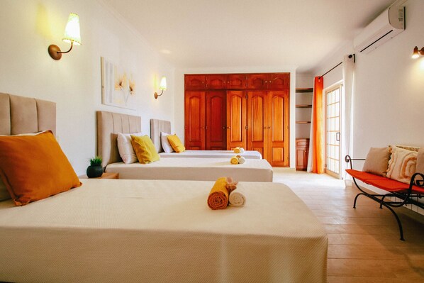 A hotel room with two beds, a bench, and a wardrobe.