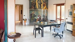 A dining area with a glass table, chairs, and a mural on the wall.