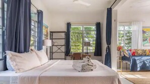 A bedroom with a bed, a desk, and a chair. There are curtains on the windows, and a painting on the wall.