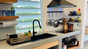 A modern kitchen with a black sink, stainless steel pots, and a range hood.
