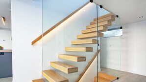 A modern staircase with glass railings and wooden steps. - 4 bedroom accommodation in Torpoint (Torpoint)