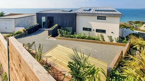 A modern house with a flat roof, a large window, and a view of the sea. - 4 bedroom accommodation in Torpoint (Torpoint)
