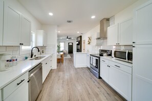 A modern kitchen with white cabinetry, a dishwasher, a microwave, and a stove. - Charming San Antonio Home ~ 2 Mi to The Alamo! (San Antonio)