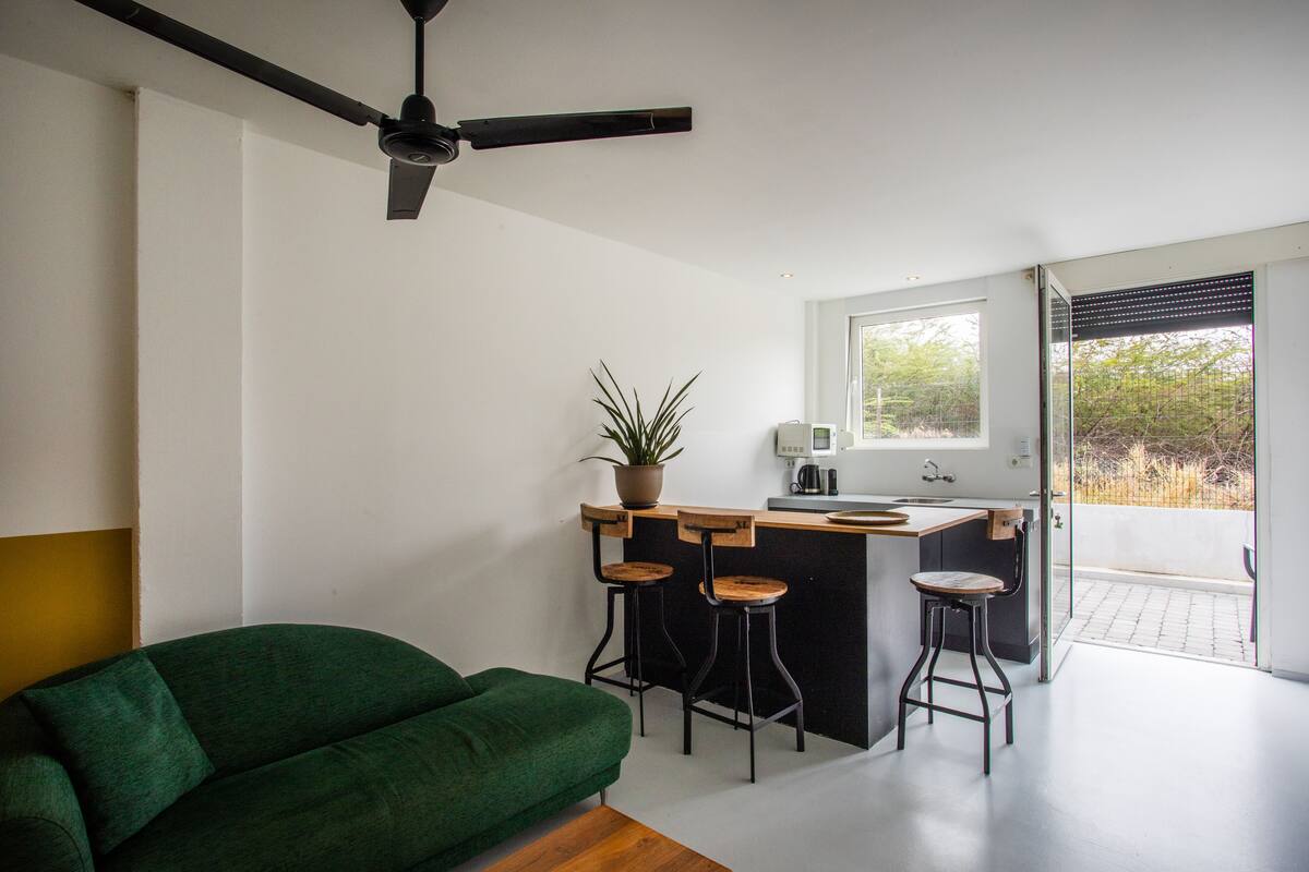 Una cocina moderna con barra, un sofá verde y un ventilador de techo.