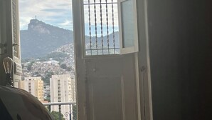 A room with a view of a cityscape, a window with a metal grille, and a door. - Panorama Inn (Rio de Janeiro)