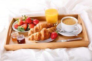 A breakfast tray with croissants, strawberries, honey, orange juice, and coffee on a bed. - Panorama Inn (Rio de Janeiro)