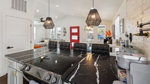 Een moderne keuken met een zwart marmeren aanrecht, een ingebouwd fornuis en een eethoek met zwarte stoelen.