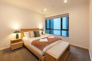 A bedroom with a bed, two bedside tables, a window, and a nightstand.