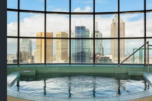 A swimming pool with a cityscape view through large windows.