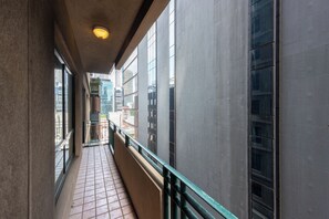 A corridor with tiled flooring, a green railing, and large windows.