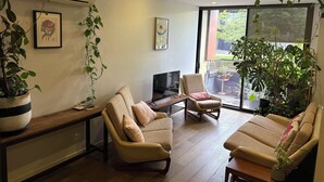 A living room with two sofas, a coffee table, a TV, and a large window with a view of the outdoors. - Cozy 1Bed Unit in leafy Carlton - 10 mins from CBD (Carlton)