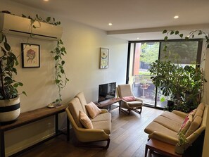 A living room with two sofas, a coffee table, a TV, and a large window with a view of the outdoors. - Cozy 1Bed Unit in leafy Carlton - 10 mins from CBD (Carlton)