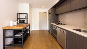 Eine moderne Küche mit Holzarbeitsplatte, integriertem Mikrowellenherd, einem Edelstahlkühlschrank und einem Gasherd.