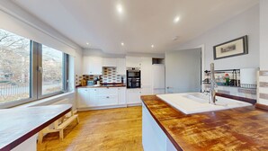 A modern kitchen with white cabinetry, a wooden countertop, and a large window. - Bannister House | Oxford Holiday Let | 5 Beds & Sleeps 9 (Oxford)