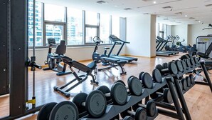 Une salle de sport équipée de matériel d’exercice, dotée de grandes fenêtres et d’un plancher en bois.