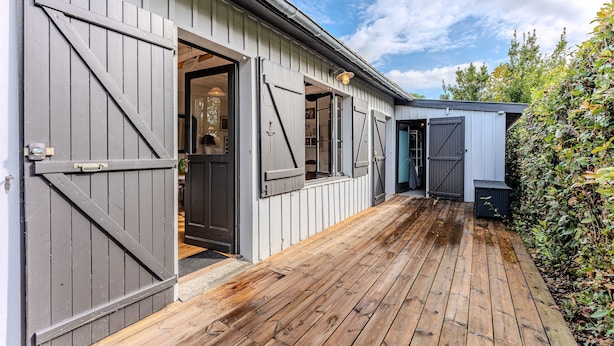 A building with large wooden doors, a wooden deck, and a garden area. - Holiday Home 'Villa Cap Ferret Centre Ref 222' with Private Terrace (CAP-FERRET)