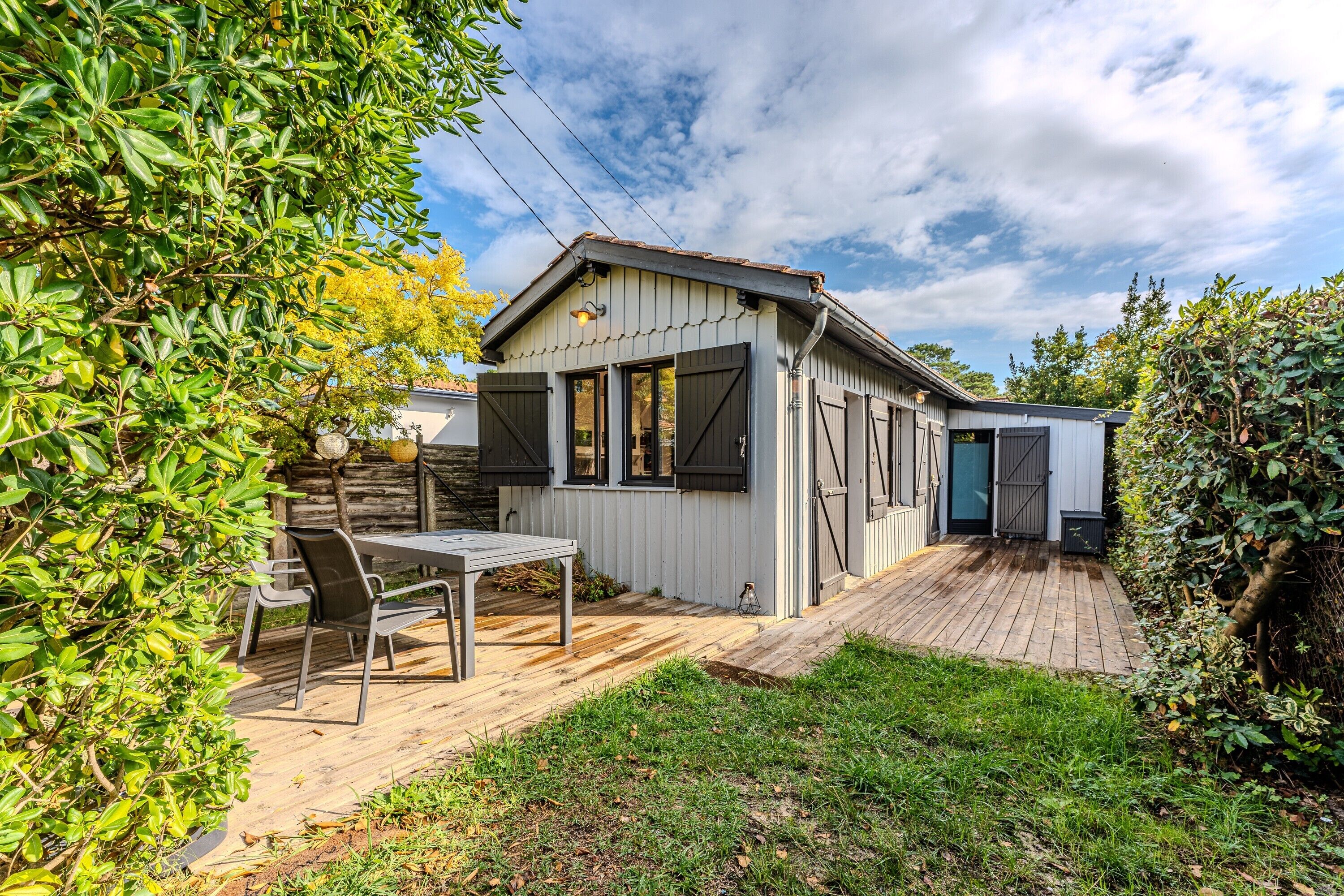A wooden deck with a table and chairs, a small shed, and a garden area.
