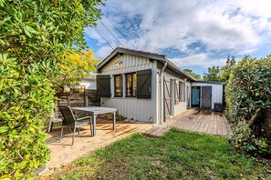 A wooden deck with a table and chairs, a small shed, and a garden area.