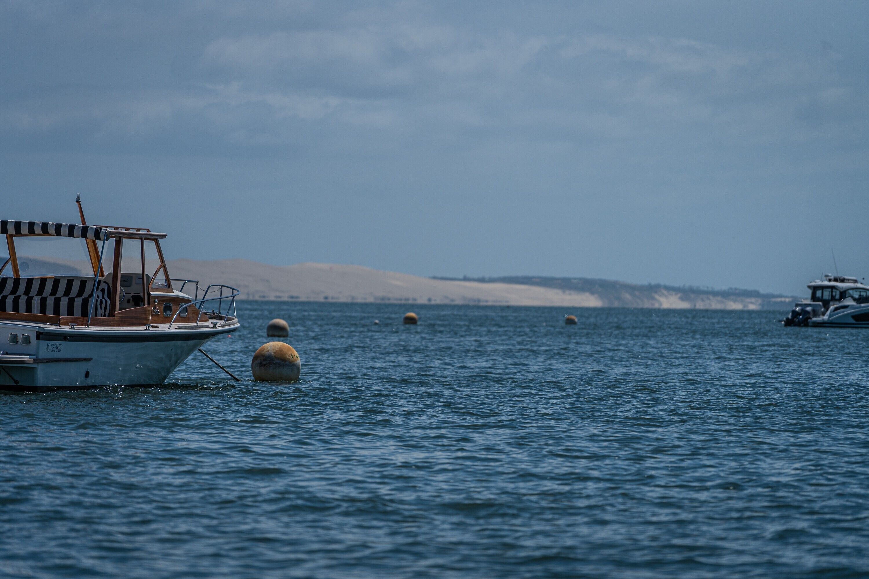 A boat on calm water with buoys and distant land.