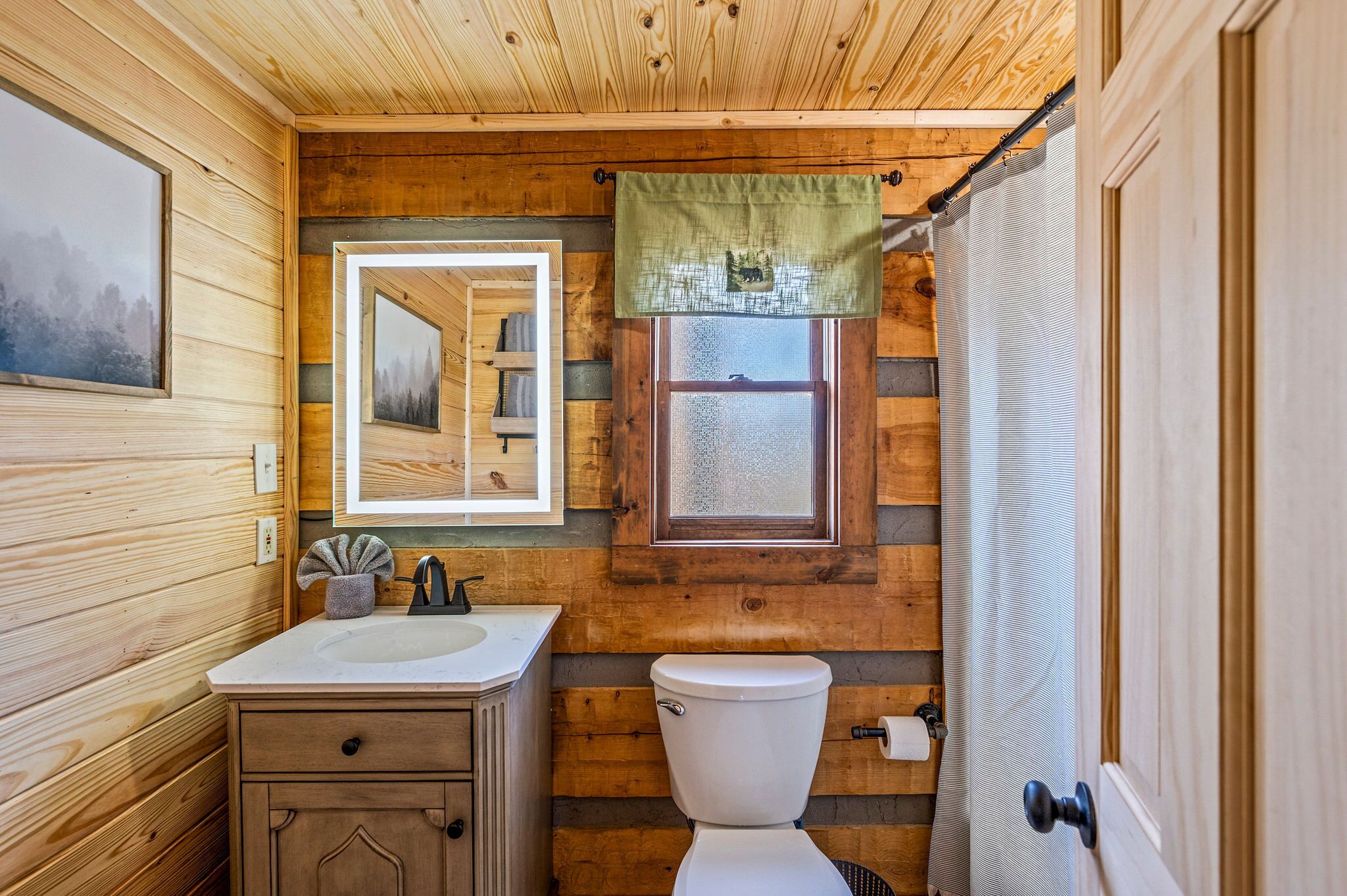 Une petite salle de bain en bois, comprenant un lavabo, des toilettes et un miroir.