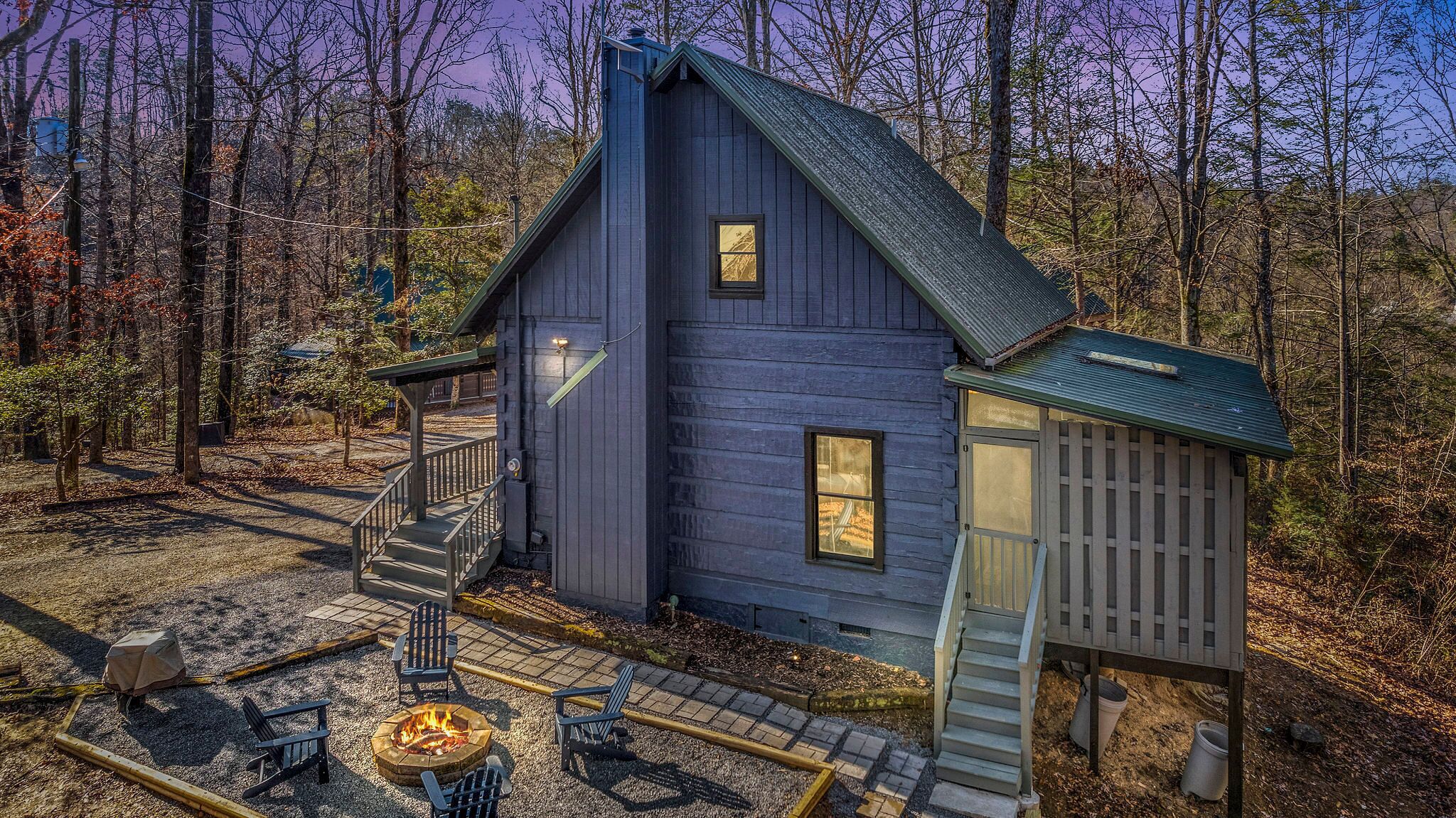 Eine Hütte mit Feuerstelle, Sitzgelegenheiten im Freien und einer Treppe zu einer Terrasse.