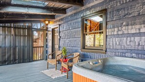 A wooden deck with a hot tub, wicker chairs, and a small table with a plant. - The Willows (Sevierville)