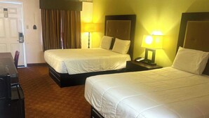 Habitació d'hotel amb dos llits, un escriptori i una cadira.