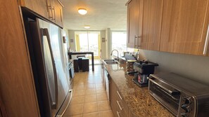A kitchen with wooden cabinets, a stainless steel refrigerator, a built-in oven, and a coffee maker.