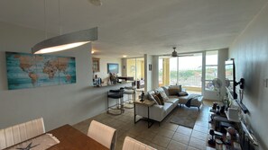 A spacious living area with a large sofa, a dining table, and a kitchen area with a bar.
