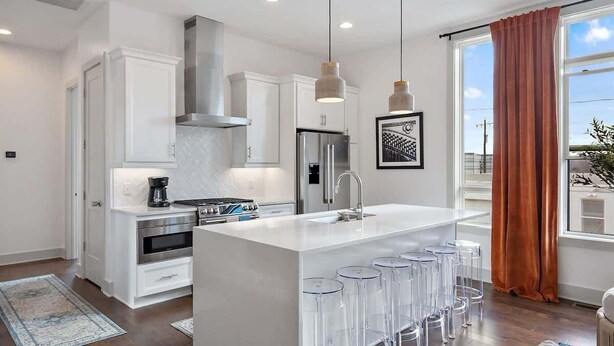 A modern kitchen with white cabinetry, stainless steel appliances, and a central island with bar stools.