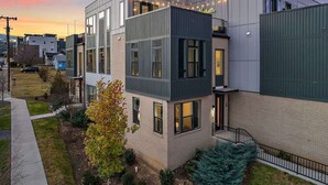 A modern multi-story building with a flat roof, large windows, and a visible balcony.