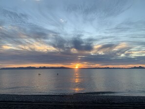 A sunset over a calm body of water with a distant mountain range.