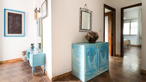 Um corredor com um armário azul, um espelho e obras de arte emolduradas nas paredes.