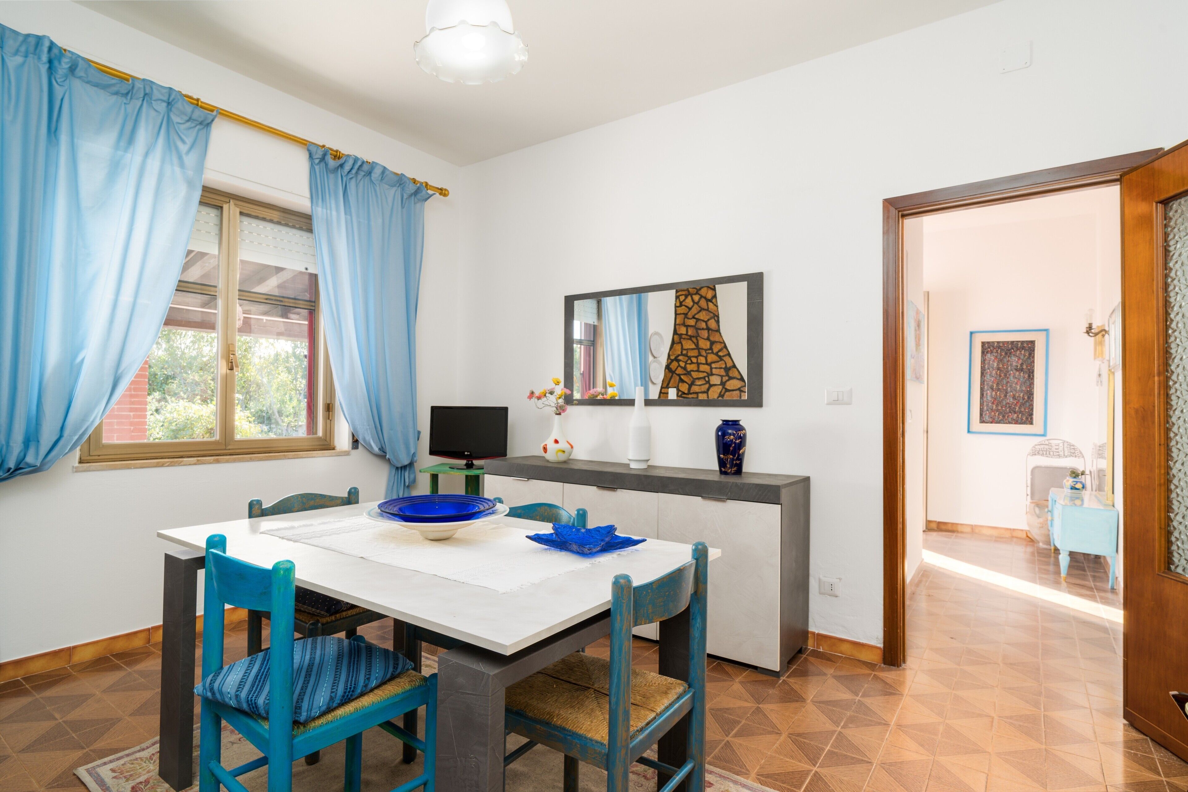 Un comedor con mesa, sillas, televisor y mostrador de cocina.